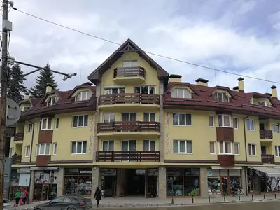 a large yellow building with a brown roof at BOROVETS Royal Plaza - A405 in Borovets
