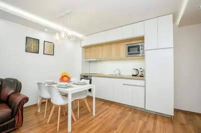 a kitchen with white cabinets and a table and chairs at Dream Park Apartment in Sandanski