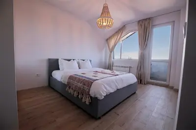 a bedroom with a bed and a large window at Pinewood Apartment Borovets in Borovets