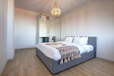 a bedroom with a large bed and a chandelier at Pinewood Apartment Borovets in Borovets