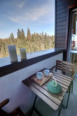 a table on a balcony with a laptop on it at Pinewood Apartment Borovets in Borovets