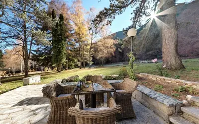 a patio with a table and chairs in a park at ШАЛЕТ БЕАТРИС in Razlog