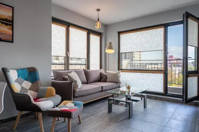 a living room with a couch and chairs and windows at Boutique 1-bedroom flat in the heart of the city in Plovdiv
