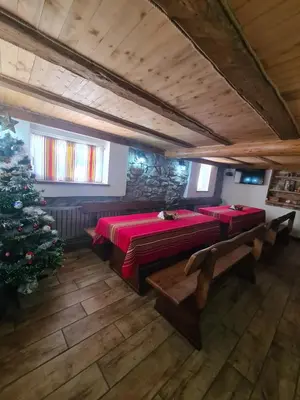 a room with two tables and a christmas tree at Мальовица - къща за гости in Dospey Makhala