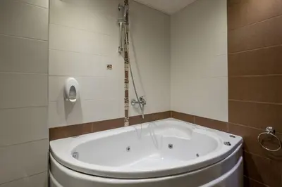 a bath tub in a bathroom with a toilet at Хотел Том и Нези Класик in Velingrad