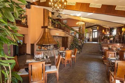 a restaurant with tables and chairs and a fireplace at Хотел Том и Нези Класик in Velingrad