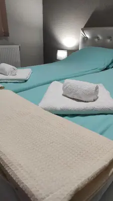 two beds with white sheets and towels on them at BeLApartment in Petrich