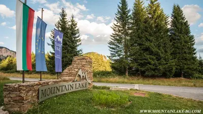 a sign for a mountainine inn with flags on a road at Studio 6,Smolyan lakes in Smolyan