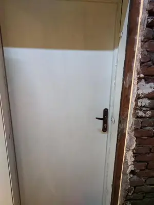 a white door in a room with a brick wall at Midtown Place Apartment Loft таванска стая с баня DORIS 2 in Plovdiv