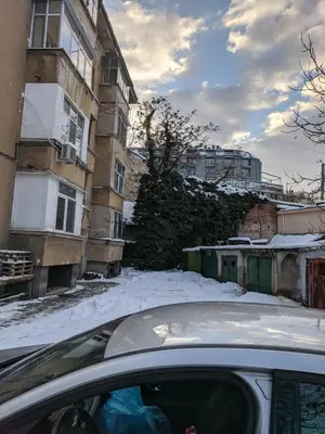a car parked in front of a building in the snow at Midtown Place Apartment Loft таванска стая с баня DORIS 2 in Plovdiv