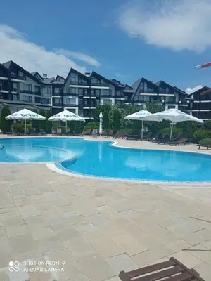 a large swimming pool with umbrellas in front of a building at Апартамент-студио в Банско-Разлог,Aspen Golf- C206 in Bansko