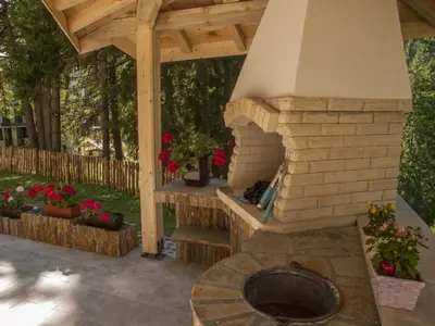 a brick oven in a patio with a wooden roof at Ски студио Снежанка в Грийн лайф Пампорово in Pamporovo