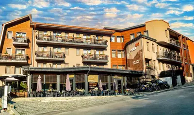 a building with tables and chairs in front of it at Hotel COTA1110 in Beli Iskar
