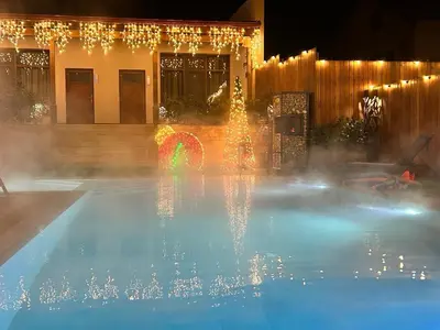 a pool with a rainbow fountain in front of a building at Guest house Wishmore in Banya