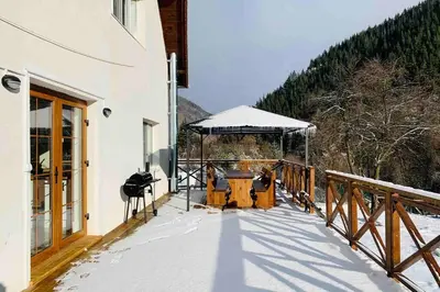 a deck with a table and a gazebo in the snow at Villa Aquila in Beli Iskar