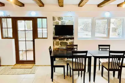 a dining room with a table and chairs and a tv at Villa Aquila in Beli Iskar