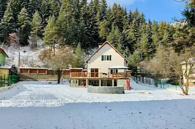a house in the snow with trees in the background at Villa Aquila in Beli Iskar