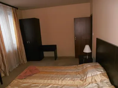 a bedroom with a bed and a chair and a window at Royal House Apartments TMF in Pamporovo