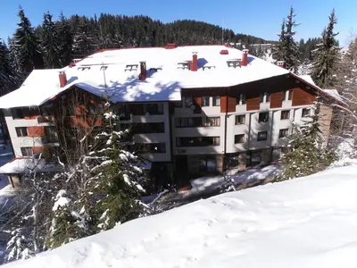 a building with snow on top of a mountain at Royal House Apartments TMF in Pamporovo