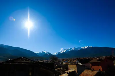 a sun over a city with mountains in the background at Family Hotel Chichin in Bansko