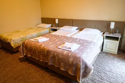 a hotel room with two beds and two tables at Family Hotel Chichin in Bansko