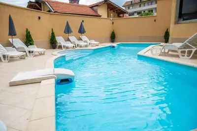 a swimming pool with white chairs and chairs in a building at Хотел Дани in Sandanski