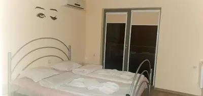 a white bed in a room with a glass door at Хотел Дани in Sandanski