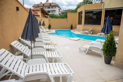 a row of white lounge chairs next to a swimming pool at Хотел Дани in Sandanski