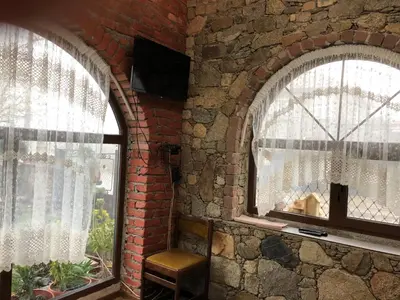 two windows in a brick wall with a chair next to them at Лилянината къща in Kalofer