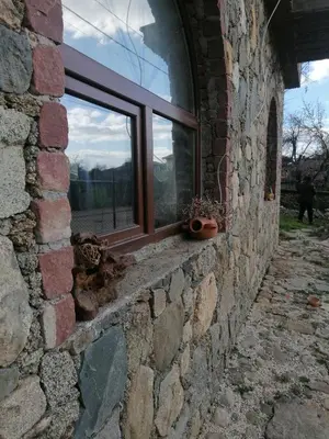 a window in a brick wall with potted plants on it at Лилянината къща in Kalofer