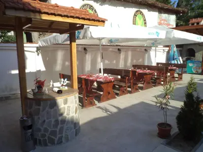 a group of tables and chairs under an umbrella at Tzvetelina Palace Hotel in Dolna Banya
