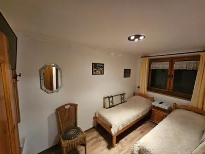 a bedroom with two beds and a chair and a window at Hotel Rai in Koprivshtitsa