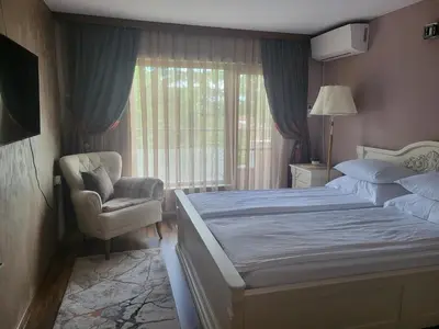 a bedroom with a bed and a chair and a window at Студио Лидия in Velingrad