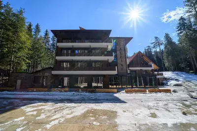a large building in the snow with the sun behind it at 103 Alpine Hotel in Panichishte