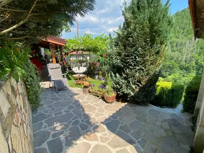 a patio with chairs and plants and trees at Къща за гости Хаджиевата къща in Smolyan