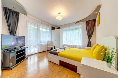 a bedroom with a yellow bed and a flat screen tv at Къща за гости Хаджиевата къща in Smolyan