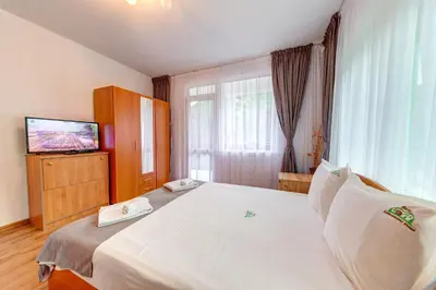 a bedroom with a large white bed with a television at Къща за гости Хаджиевата къща in Smolyan