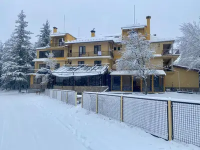 a building with a snow covered yard in front of it at Хотел Сима in Beklemeto
