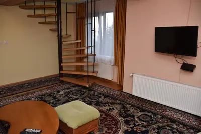 a living room with a table and a tv on a wall at Хотел Сима in Beklemeto