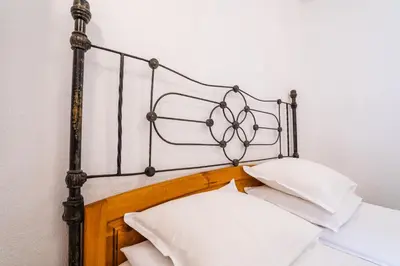a bed with a metal head board with white pillows at Toni's Guest House in Melnik