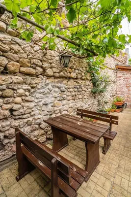 two wooden benches sitting in front of a stone wall at Toni's Guest House in Melnik