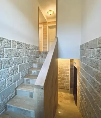 a staircase in a house with a stone wall at Къща за гости Volpe - Volpe Guesthouse in Oreshak
