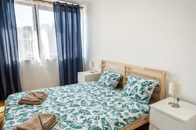 a bedroom with a bed and a window with blue curtains at Bendida Central in Velingrad