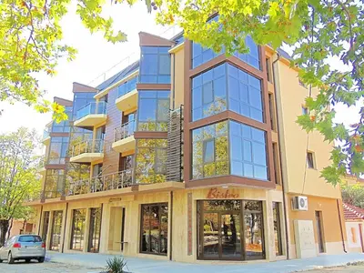 a tall building with glass windows on a street at Fantasy Apartaments and studios Avenue комплекс Фантазия Хисаря in Hisarya