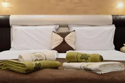 a bed with white pillows and towels on it at Fantasy Apartaments and studios Avenue комплекс Фантазия Хисаря in Hisarya