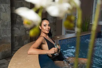 a woman sitting in a bath tub with a glass of wine at Villa Pino in Velingrad
