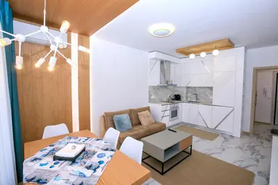 a living room and kitchen with a table and a dining room at Лукс Апартамент Радост 2 in Sandanski