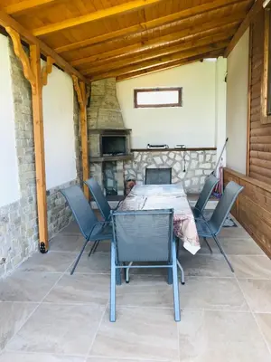 a table and chairs on a patio with a fireplace at Къщи за гости Михайлови in Sapareva Banya