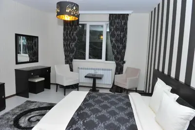 a bedroom with a bed and chairs and a window at Eros Motel in Sandanski