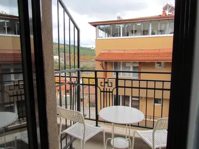 a balcony with a table and chairs and a building at Апартаменти Елеганс in Sandanski